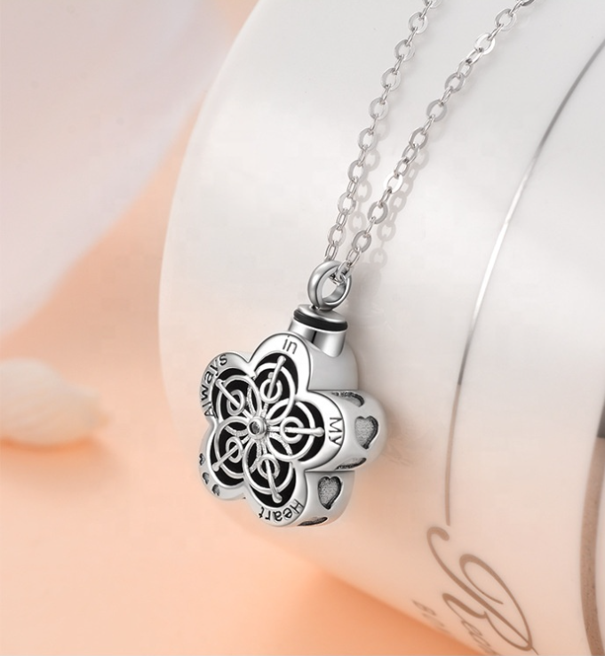 Silver cremation necklace with a floral pendant on a soft pink background