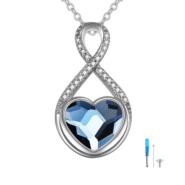 Sterling Silver Cremation Jewelry necklace with an infinity symbol and blue heart-shaped gem on a white background